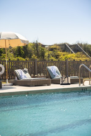 A pool area with two lounge chairs, a lifebuoy, and a wooden fence. - Oceanside King Suite | Near Pool + Private Beach (Duck)