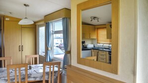 Eine kleine Küche mit Holzausstattung, einer Marmorarbeitsplatte und einem Fenster mit Vorhängen.