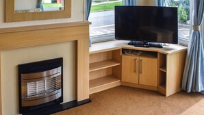Ein modernes Wohnzimmer mit Flachbildfernseher, einer Holz-Unterhaltungseinheit und einem Kamin.