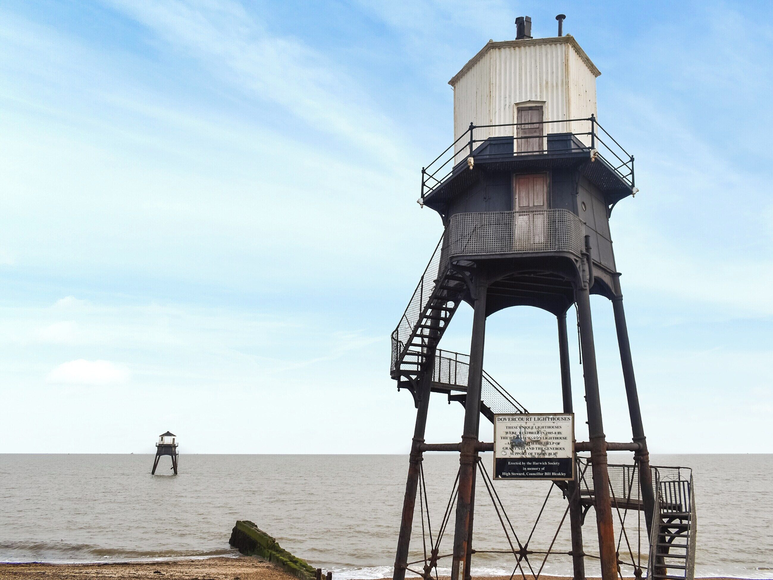 Un faro con una scala in metallo e una targa, situato vicino alla costa.