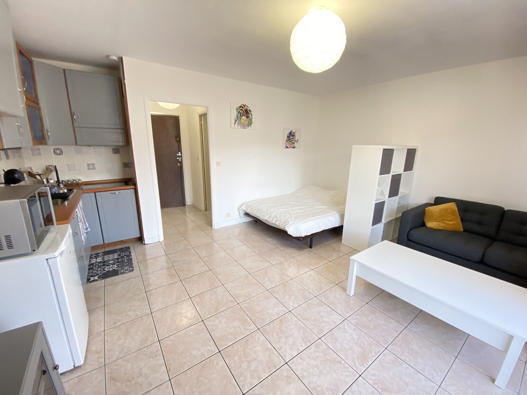 A compact living space with a kitchenette, a bed, a sofa, and a small dining table.