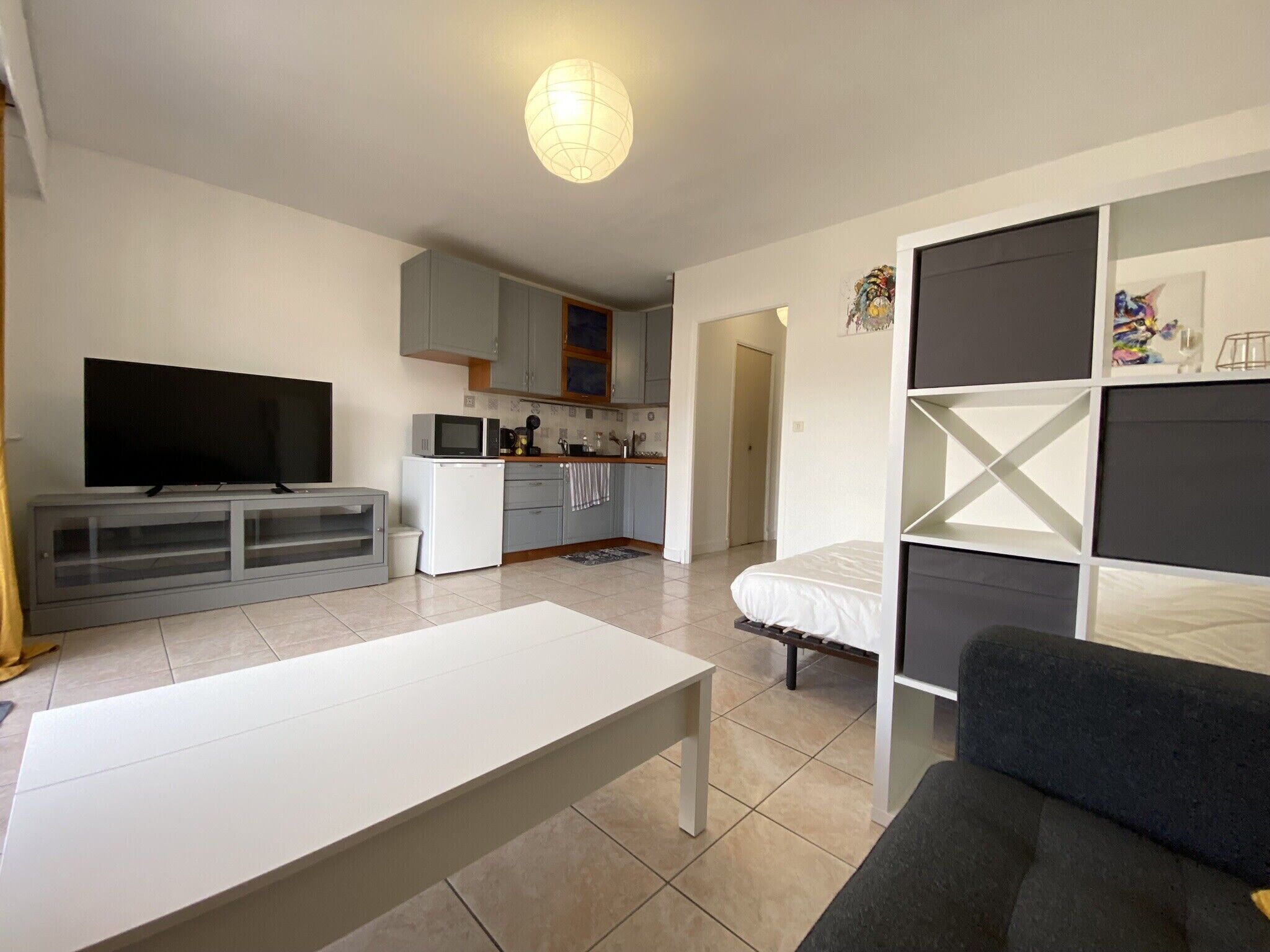 Un espace de vie compact comprenant un téléviseur, une kitchenette et un canapé.