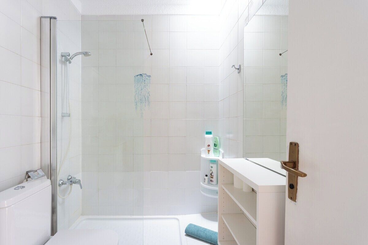 A modern bathroom with a glass shower enclosure, a white sink, and a mirror.