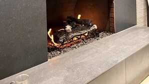 Une cheminée moderne dotée d’un banc intégré, un pichet en verre transparent et un mur à texture.