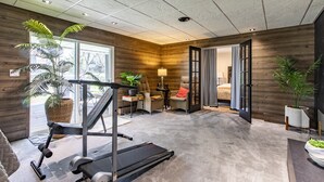 Une salle de sport moderne, équipée d’un tapis de course, de poids et d’une grande fenêtre.
