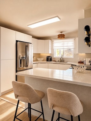 A modern kitchen with a central island, stainless steel appliances, and bar stools. - Canal Waterfront ocean side w boat ramp & Hot Tub. Sleep 8 in Key Largo (Key Largo)
