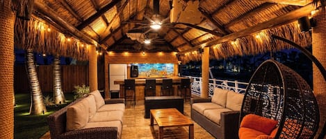 An outdoor seating area with wicker furniture, a hanging chair, and a bar area with a mural.