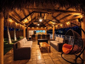 An outdoor seating area with wicker furniture, a hanging chair, and a bar area with a mural.