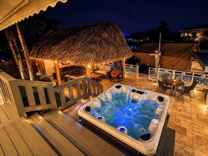A hot tub with a wooden deck, a thatched-roof lounge area, and a poolside setting. - Canal Waterfront ocean side w boat ramp & Hot Tub. Sleep 8 in Key Largo (Key Largo)