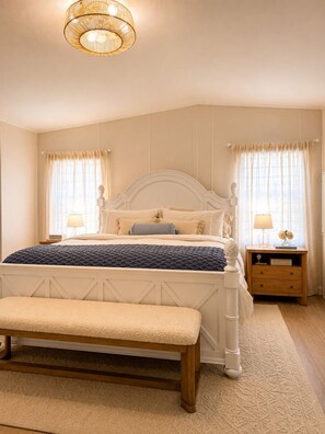 A bedroom with a large bed, a bench, two bedside tables with lamps, and a hanging light fixture. - Canal Waterfront ocean side w boat ramp & Hot Tub. Sleep 8 in Key Largo (Key Largo)