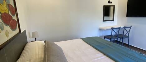 A bedroom with a bed, a desk, and a chair.