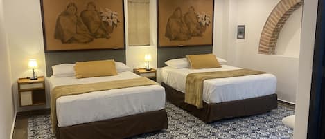 A hotel room with two beds, a patterned floor, and artwork on the walls.