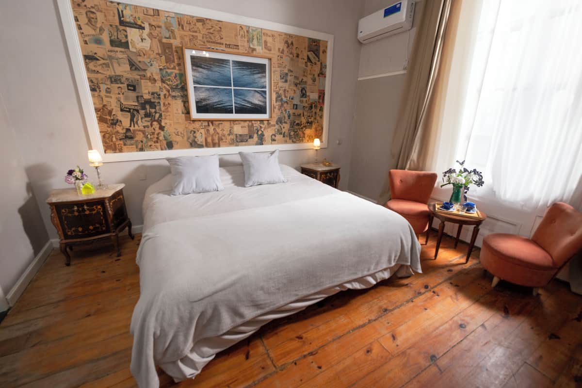 A hotel room with a large bed, two nightstands, a chair, a small table, and a wall decorated with a collage of images.