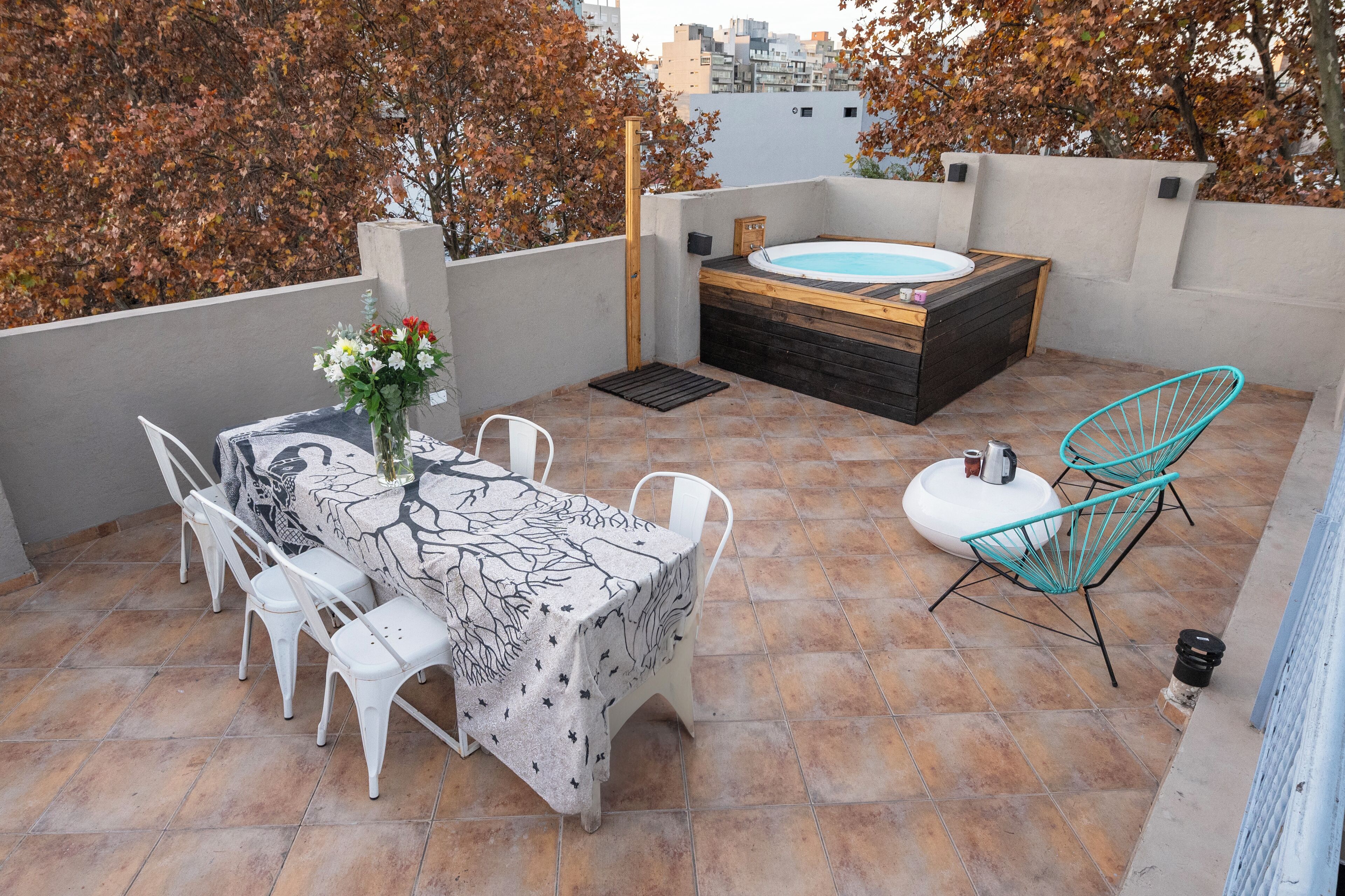 Une terrasse sur le toit avec un jacuzzi, une table à manger avec des chaises et un vase décoratif.
