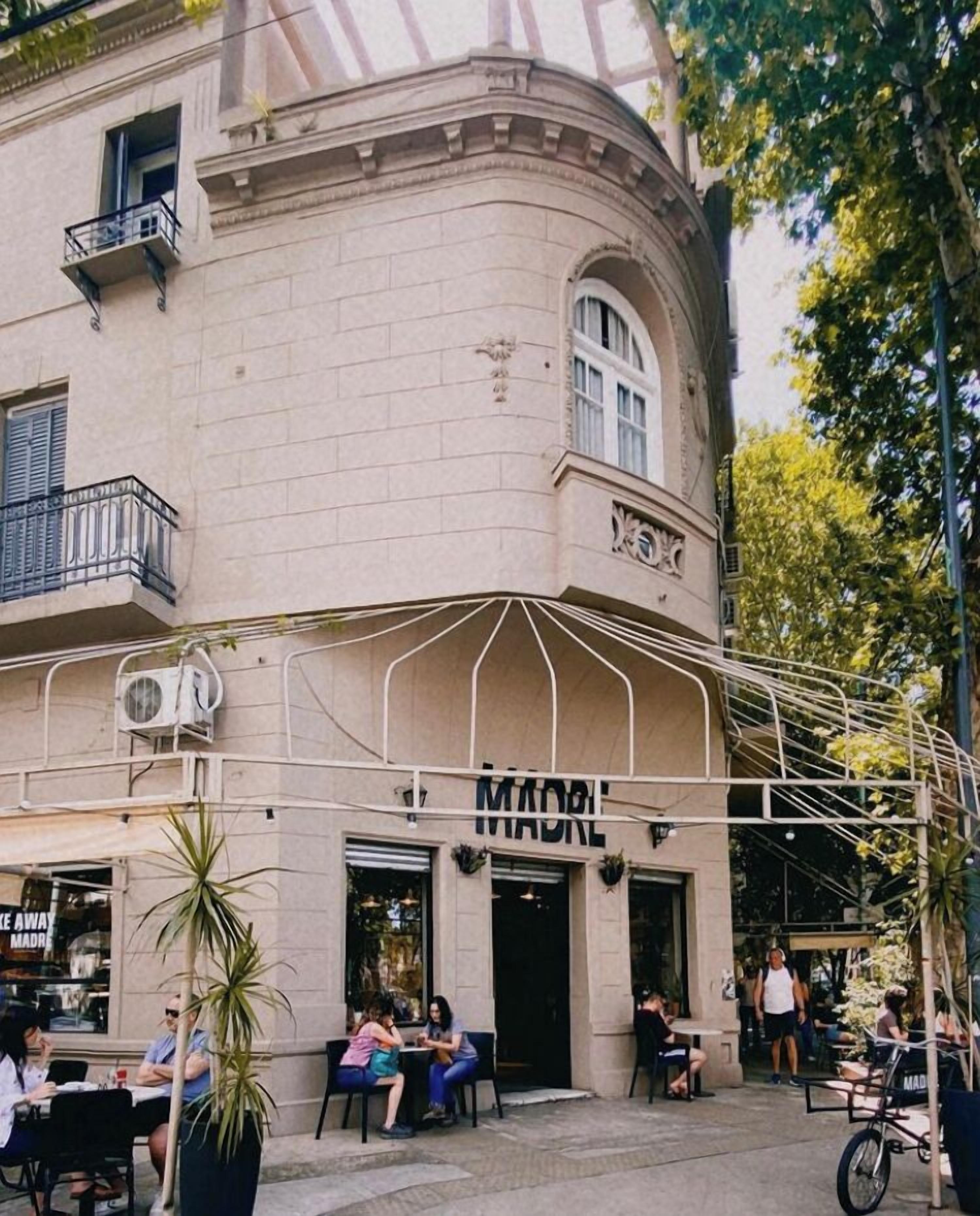 Un bâtiment sur lequel on peut lire l’inscription « MADRE MADRE », avec une terrasse où sont assis des clients.