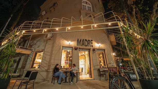 Un restaurante llamado 'MADRE' con terraza y una escalera metálica que lleva a la entrada.