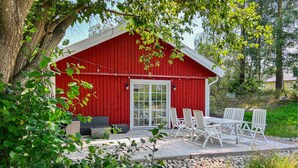 A red wooden cabin with a glass door, outdoor seating, and a stone pathway. - 3 bedroom beautiful home in Sölvesborg (Sölvesborg)