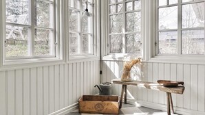 A corner room with large windows, a wooden bench, a vase with dried plants, and a kettle on the floor. - 3 bedroom beautiful home in Sölvesborg (Sölvesborg)