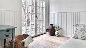 A room with a large window, a wicker chair, a small table, and a decorative pot. - 3 bedroom beautiful home in Sölvesborg (Sölvesborg)