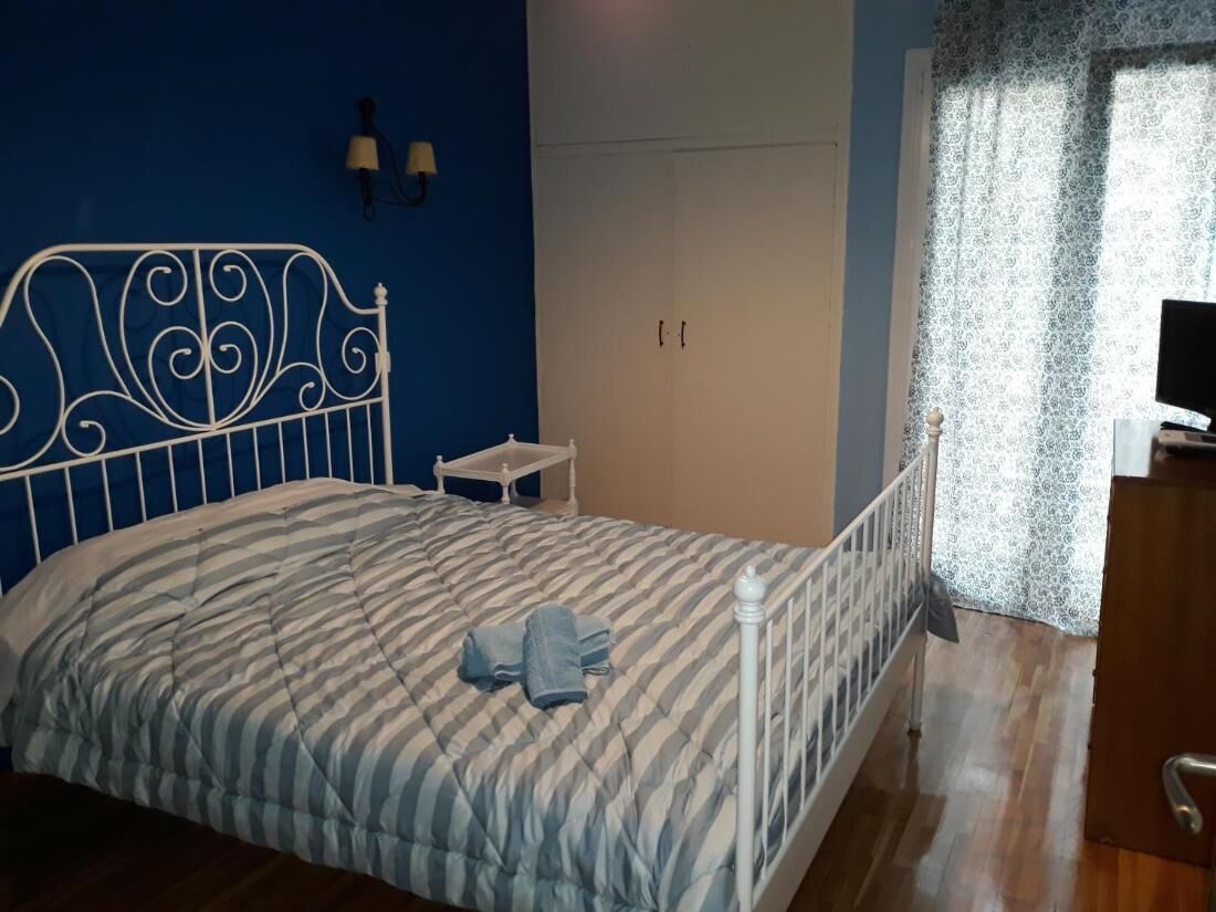 A bedroom with a bed, a wardrobe, a nightstand, and a television.