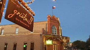 Um edifício de tijolos com uma placa que indica 'Gristmill River Restaurant & Bar' e uma placa de neon que diz 'Hut's'.