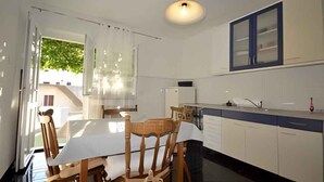 Eine moderne Küche mit Esstisch, Stühlen und einem Kühlschrank.