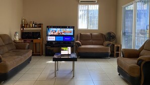 A living room with a flat-screen TV, two sofas, a coffee table, and a TV stand with a speaker. - Rancho Playa las Flores (La Libertad)