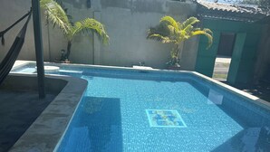 A swimming pool with a tiled pattern, surrounded by a concrete deck and palm trees. - Rancho Playa las Flores (La Libertad)