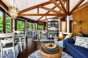 A spacious living area with a dining table, a blue sofa, and a wooden coffee table. - Sleep in a Treehouse!! (Lake Ariel)