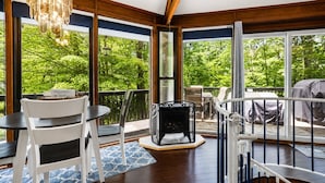A sunroom with a fireplace, large windows, and a view of greenery.