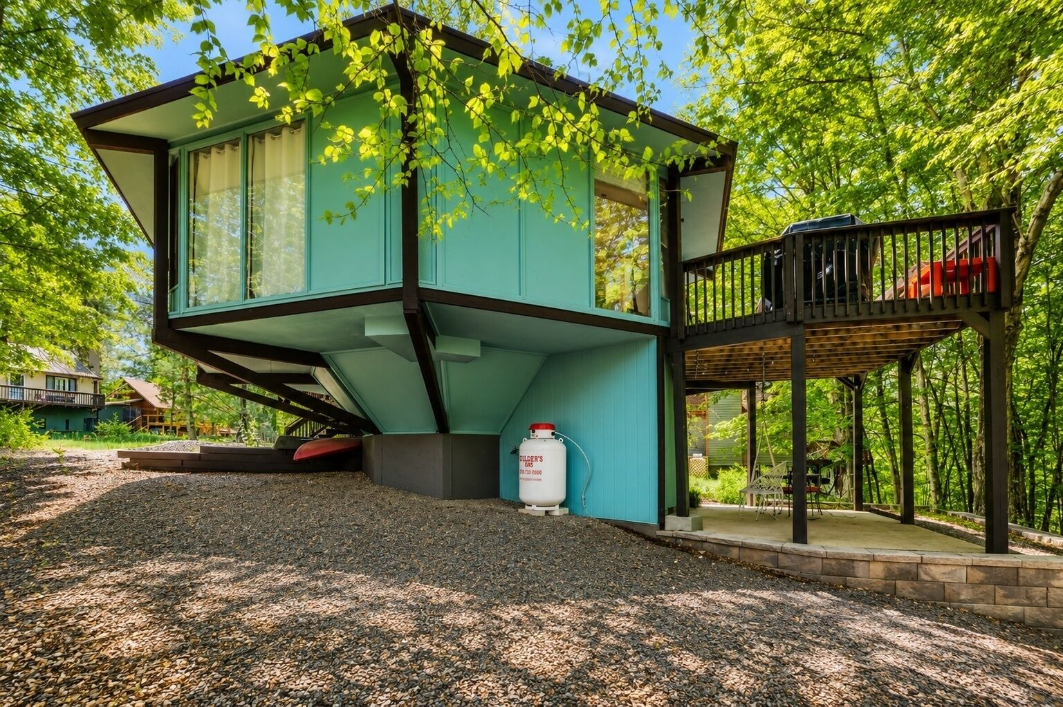 Une maison moderne à deux étages, dotée d’un balcon et entourée d’arbres.