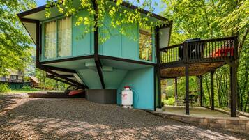 Une maison moderne à deux étages, dotée d’un balcon et entourée d’arbres.