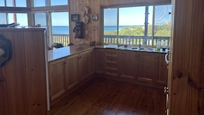 A wooden kitchen with large windows overlooking the ocean. - Ocean View Holiday Home Orchid Beach | Phippsy's On Fraser | Sleeps 20 people! (K'gari)