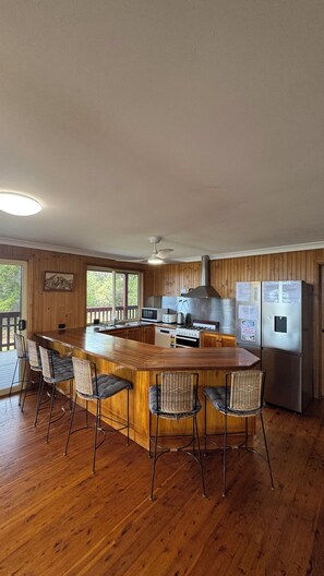 Une cuisine avec un îlot central en bois, des tabourets de bar, un four à micro-ondes, une cuisinière et un réfrigérateur.