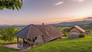 Une maison rustique avec un toit en pente, des fondations en pierre et une petite construction en bois à proximité.