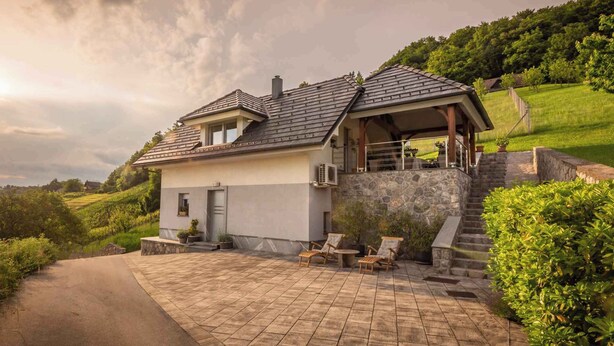 Une maison moderne avec une façade en pierre, un porche couvert et une allée pavée.