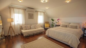 Une chambre à coucher avec un grand lit, un petit canapé, une chaise et une table de chevet avec une lampe.