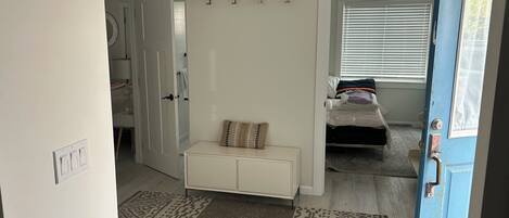 Un dormitorio con cama, mesita de noche, ventana con persianas y puerta.