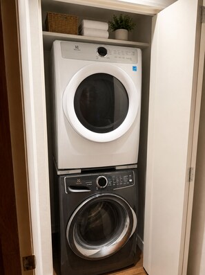 A compact laundry room with a top-loading washer and a front-loading dryer.