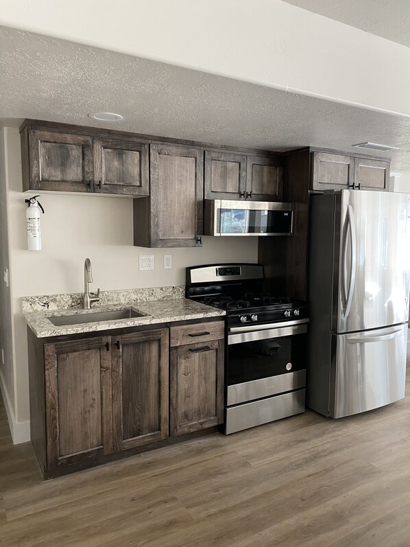 A modern kitchen with wooden cabinets, stainless steel appliances, and a granite countertop. - Spacious lodge viewing the Big Rock Candy Mountain (Sevier)