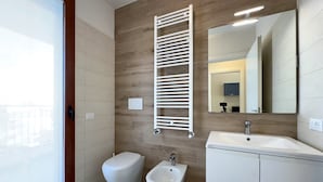 Un baño moderno con inodoro, bidé y lavamanos blanco.