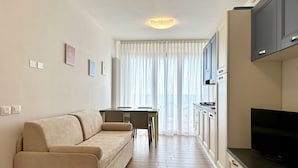 Una sala moderna con un sofá, una mesa de comedor y una zona de cocina con armarios y un televisor.