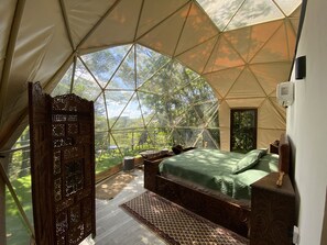 A tented accommodation with a bed, wooden furniture, and a view of the surrounding forest. - Way to Heaven Luxury Glamping (Monteverde)