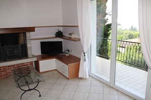A room with a TV, a fireplace, a balcony with a view, and a sliding glass door.