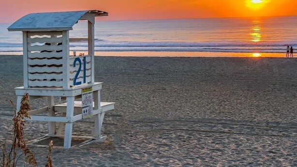 A lifeguard tower with the number 21 on a beach at sunset. - 30 Sec. to Beach, Sun, Sand & Waves  &  a Family & Pet Friendly Fenced Backyard (Carolina Beach)