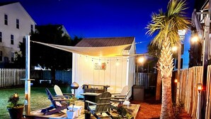 A backyard patio with outdoor furniture, string lights, and a palm tree. - 30 Sec. to Beach, Sun, Sand & Waves  &  a Family & Pet Friendly Fenced Backyard (Carolina Beach)