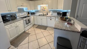 A modern kitchen with white cabinets, a granite countertop, a built-in oven, a microwave, and a coffee maker. - 30 Sec. to Beach, Sun, Sand & Waves  &  a Family & Pet Friendly Fenced Backyard (Carolina Beach)