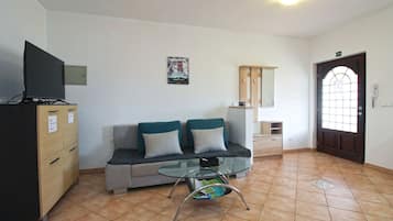 Una sala de estar con un sofá, una mesita de vidrio, un mueble aparador y una puerta con ventanal.