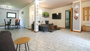Un vaste espace de vie comprenant un canapé, une table basse et un téléviseur fixé au mur.