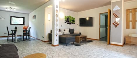 Un vaste espace de vie comprenant un canapé, une table basse et un téléviseur fixé au mur.